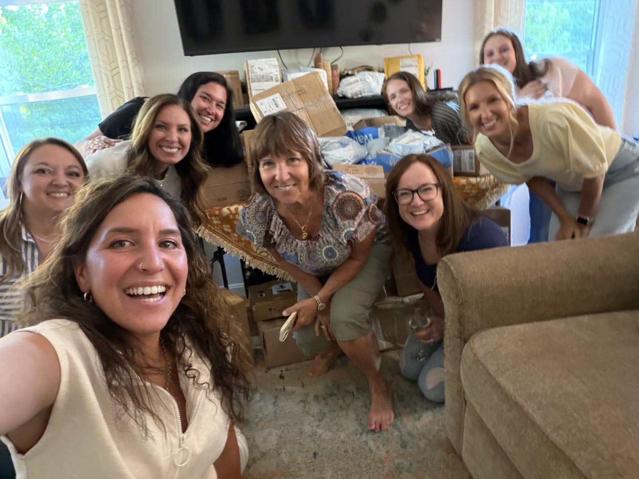 Big group selfie in front of a mountain of mystery packages