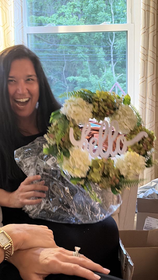 Guest thrilled with a floral 'hello' wreath unwrapped from a mystery box