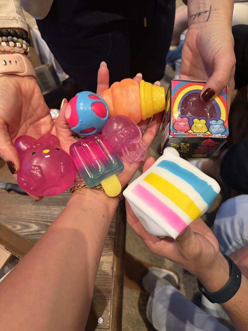 Colorful mystery party squishy toys held up by guests