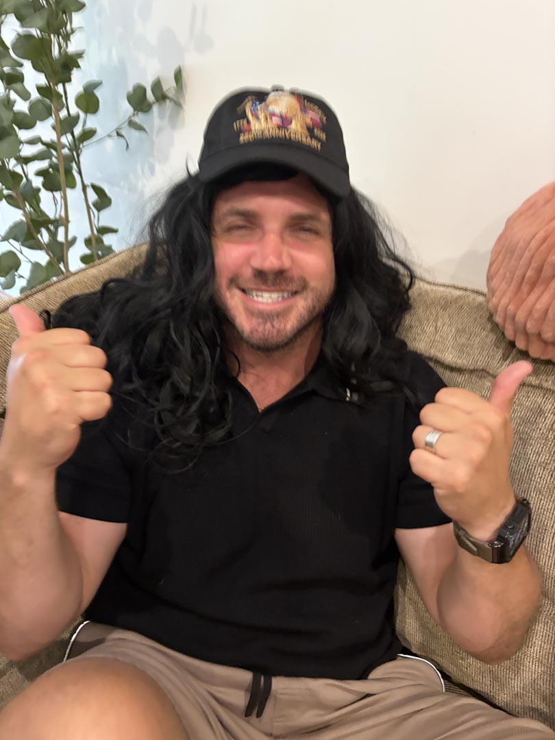 Guest wearing a mystery wig — very serious thumbs up